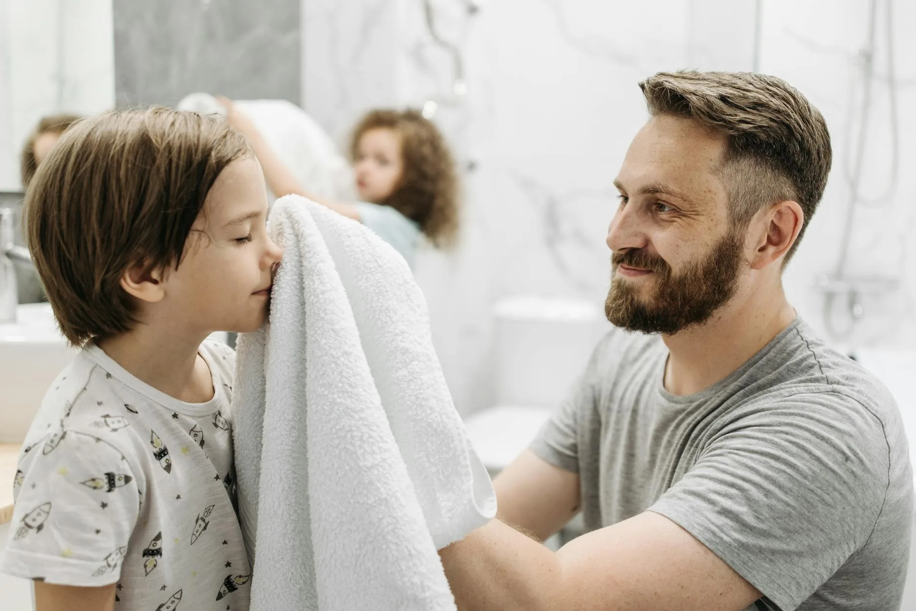 a father using towel to wipe his son