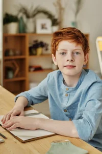 red haired boy in blue shirt sitting at desk